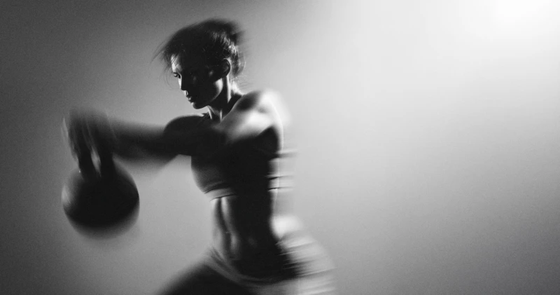 zwart-wit foto met bewegingsonscherpte van een vrouw met cattlebell