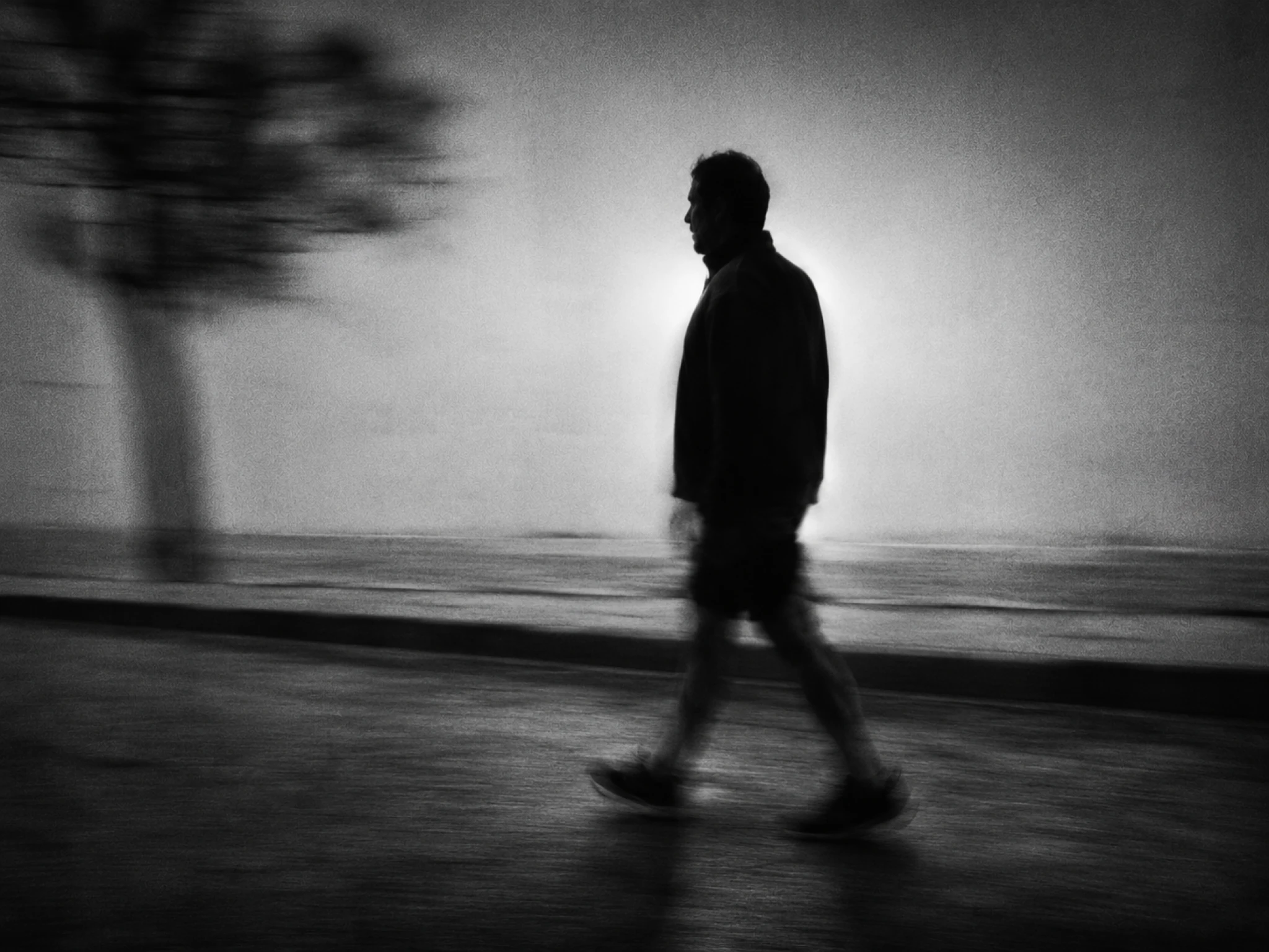 A man walks at an easy pace along an empty street in the morning, active recovery on a rest day.