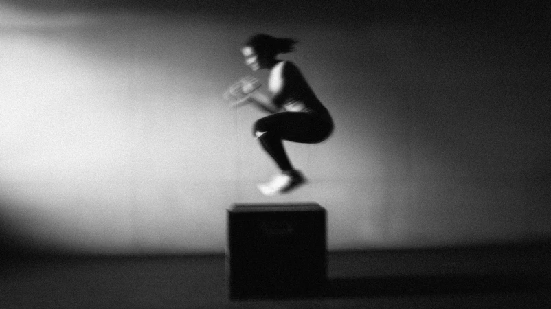 Fysieke training van jonge fitte vrouw die op een box springt